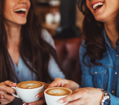 Two women drinking coffee which can cause tooth staining