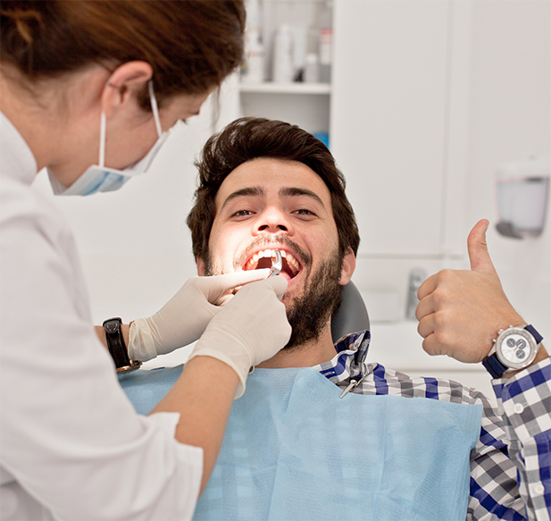 Young man giving thumbs up while undergoing a dental procedure