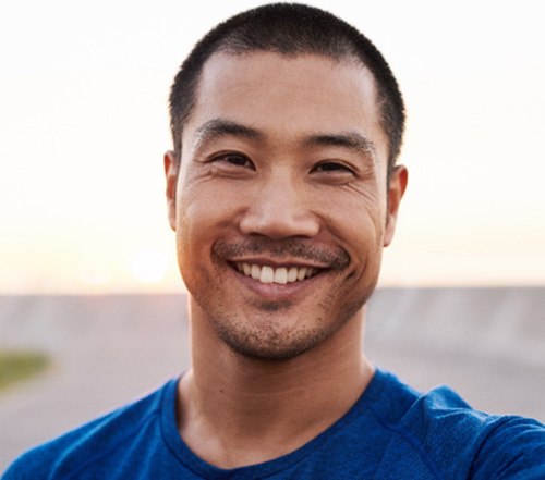 Man in blue shirt smiling while walking down a road