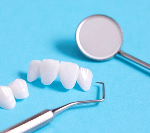 Dental bridges lying on a table with various dental tools