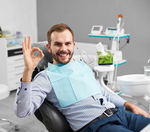 Male dental patient giving an “okay” sign