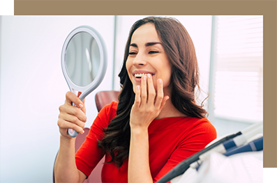 Dental patient looking at her new smile in a hand mirror