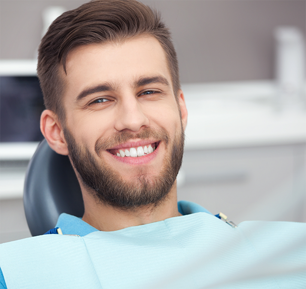 Young man with a beard smiling in the dental chair
