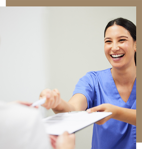 Friendly dental team member handing a clipboard to a patient