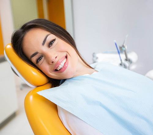 Female patient leaning back in dental chair and smiling