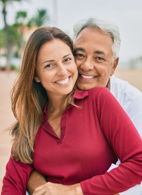 Man and woman smiling and hugging outdoors