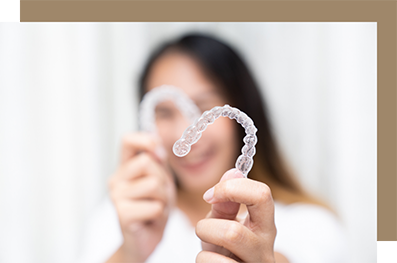 Woman holding up two clear aligners