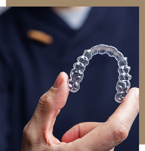Person in scrubs holding a clear aligner