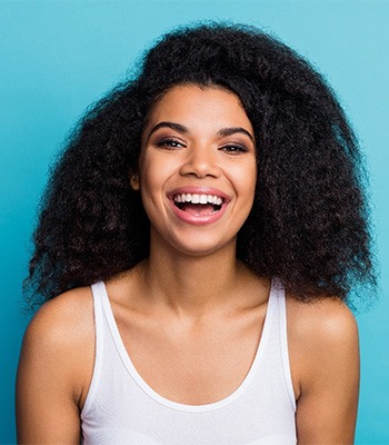 Woman with beautiful smile in white tank-top with blue background