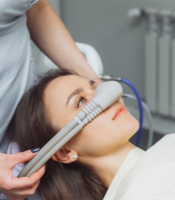 Woman with nitrous oxide mask on nose held by dentist