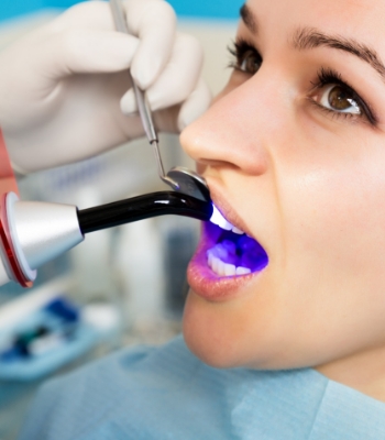 Closeup of dental mirror reflecting lower teeth with cavities