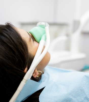 Woman with nitrous oxide mask on nose held by dentist