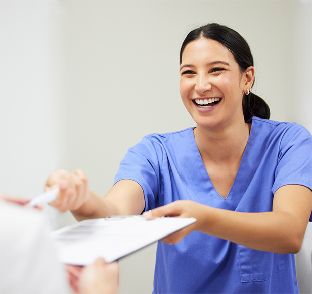 Smiling dental team member giving clipboard to a patient