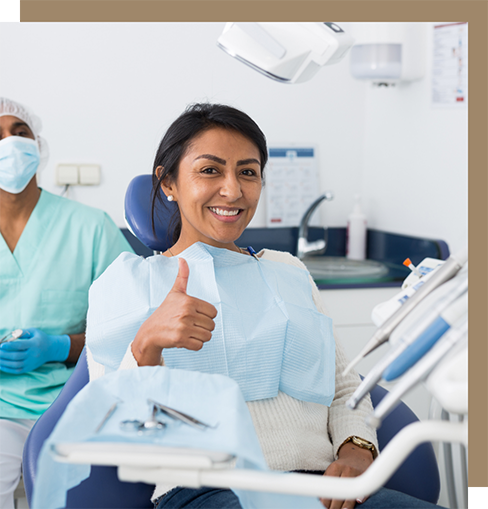 Happy young woman giving thumbs up in dental chair