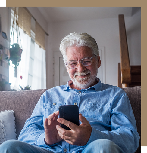 Older man in denim jacket smiling at his phone