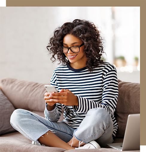 Young woman sitting on a couch and smiling at her phone