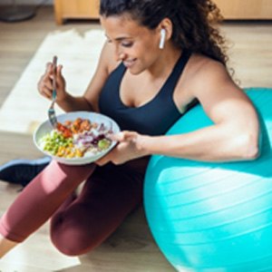 Smiling woman eating colorful salad after workout