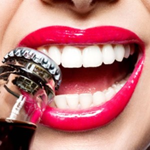 Closeup of woman opening bottlecap with teeth