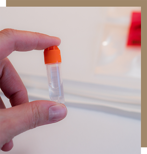 Hand holding a small vial of clear liquid
