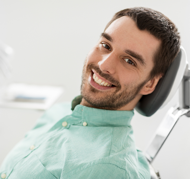 Young man leaning back in the dental chair and smiling