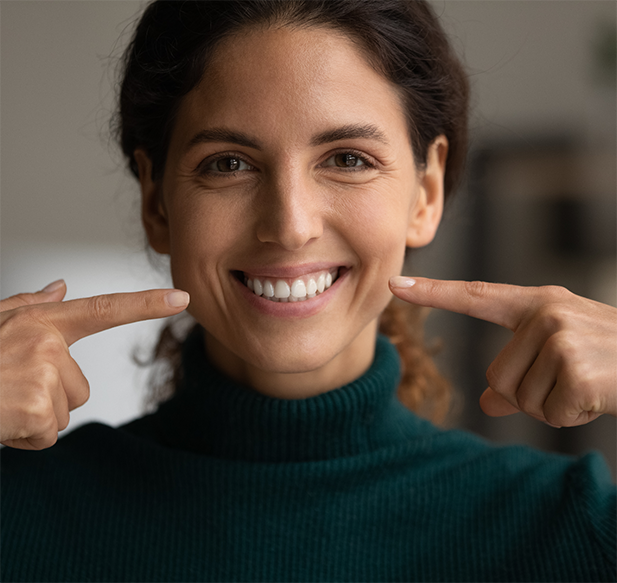 Brunette woman pointing to her smile