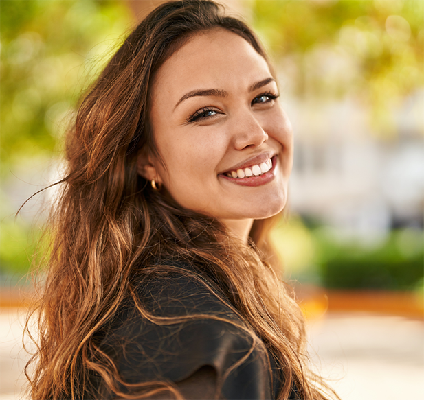 Brunette woman smiling over her shoulder in a park