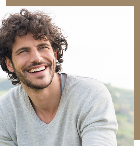 Young man with curly brown hair outside on an overcast day