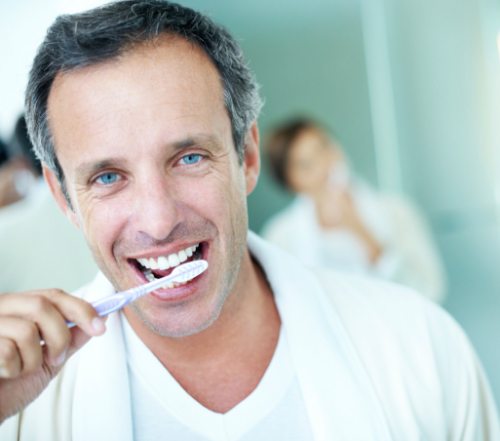 Man brushing his teeth after receiving porcelain veneers