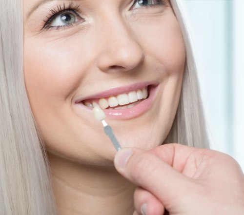 Dentist and patient discussing how to care for smile after porcelain veneers