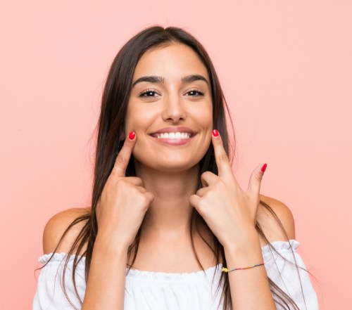 Woman pointing to smile after teeth whitening