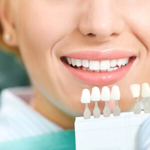 dentist holding shade scale up to patients teeth