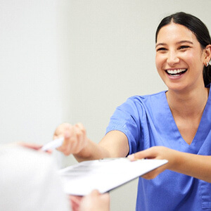 dental assistant smiling while handing patient form