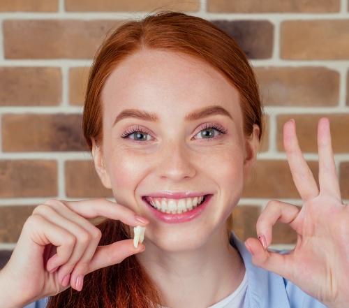 Woman holding up wisdom tooth after removal