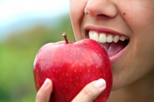 person eating apple to avoid dental emergencies
