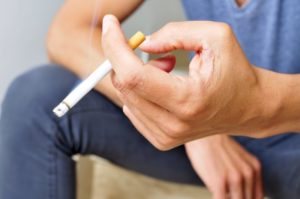 person smoking a cigarette, increasing their risk for oral cancer in Cocoa Beach 