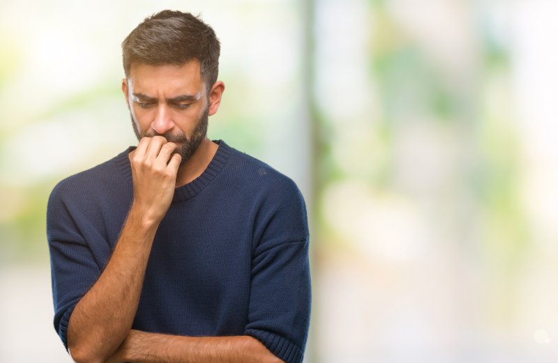 Worried man looking down at his mouth