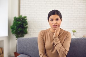 Woman touching cheek, concerned about a loose dental implant