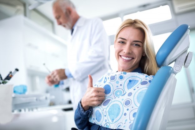 Woman visiting her cosmetic dentist and giving a thumb’s up.