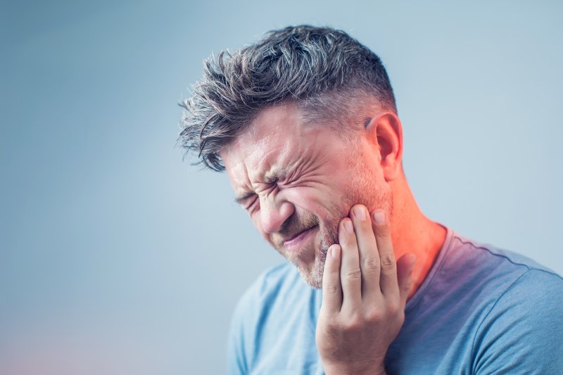 Man with tooth pain holding his cheek