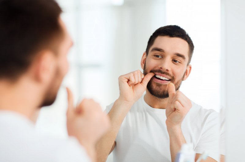 man flossing his teeth